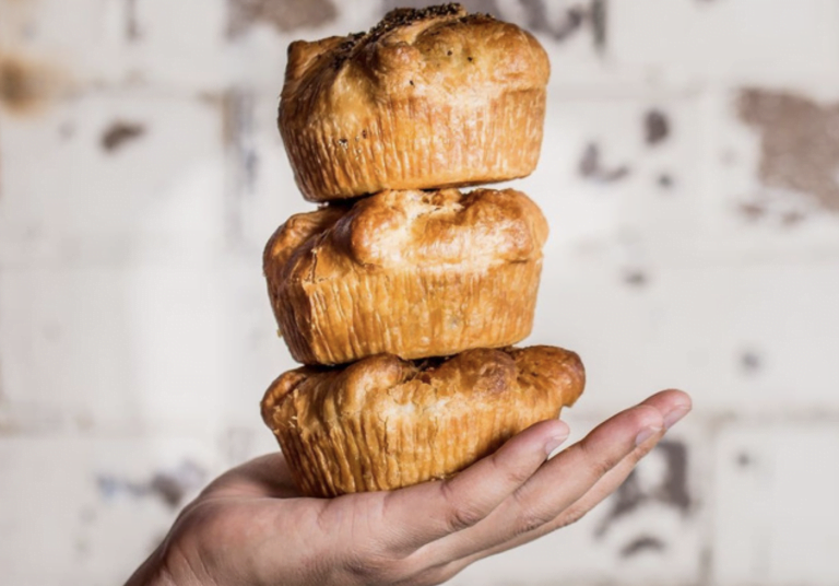 hand carrying a stack of 3 pies